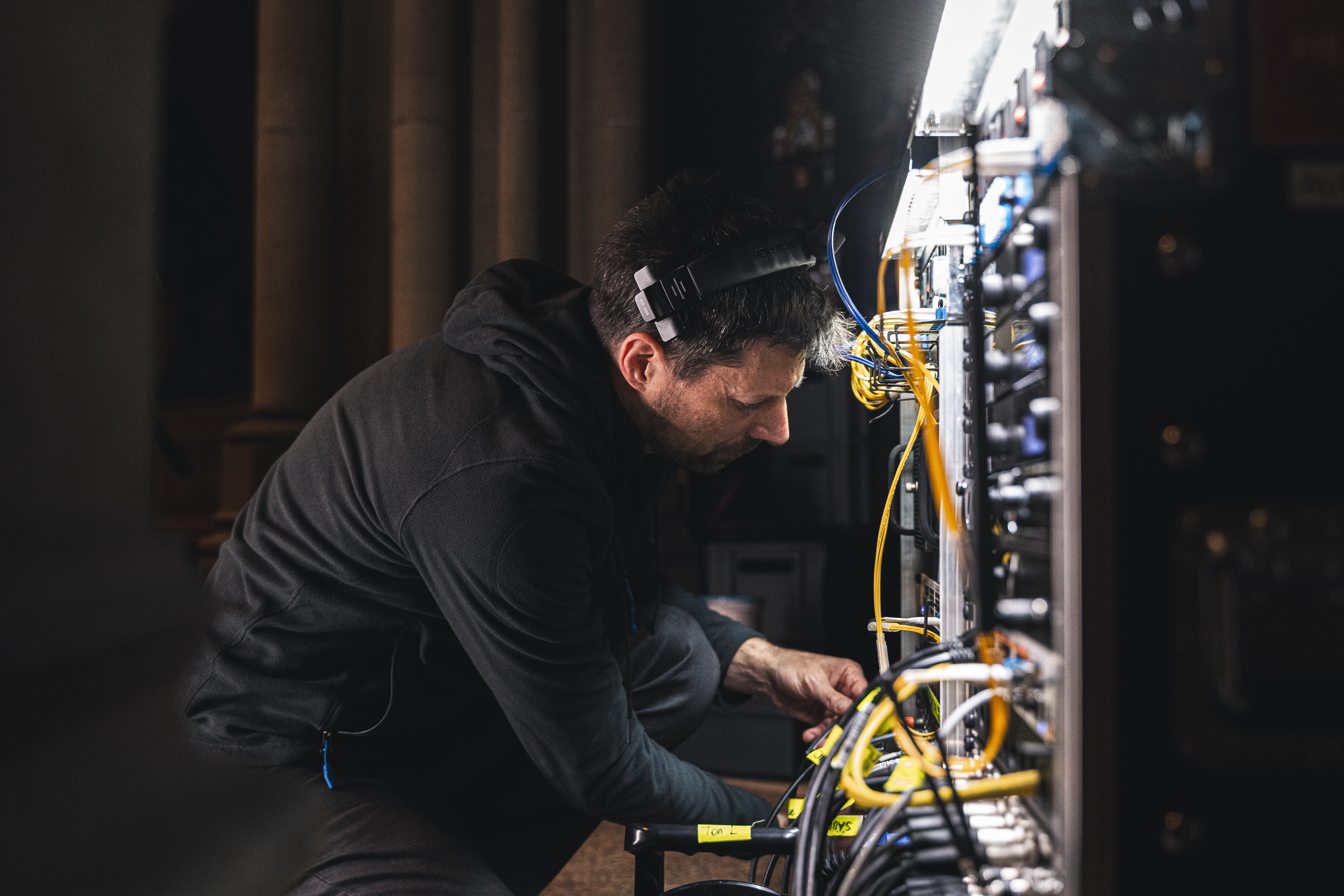 Mann mit Headset vor Racks mit Kabeln